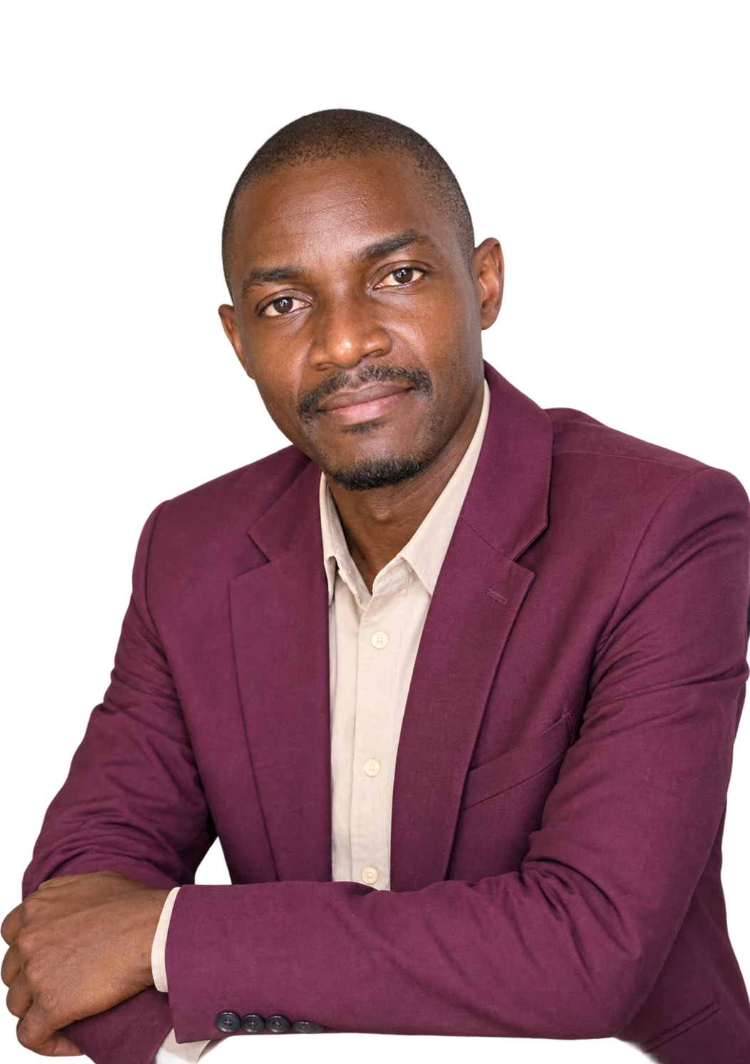 Hon. Clarence Namunyu Kasali in a maroon blazer and cream shirt, resting his arms on a table
